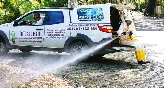 Técnico da Ambiental fazendo aplicação externa ao lado do veículo da empresa